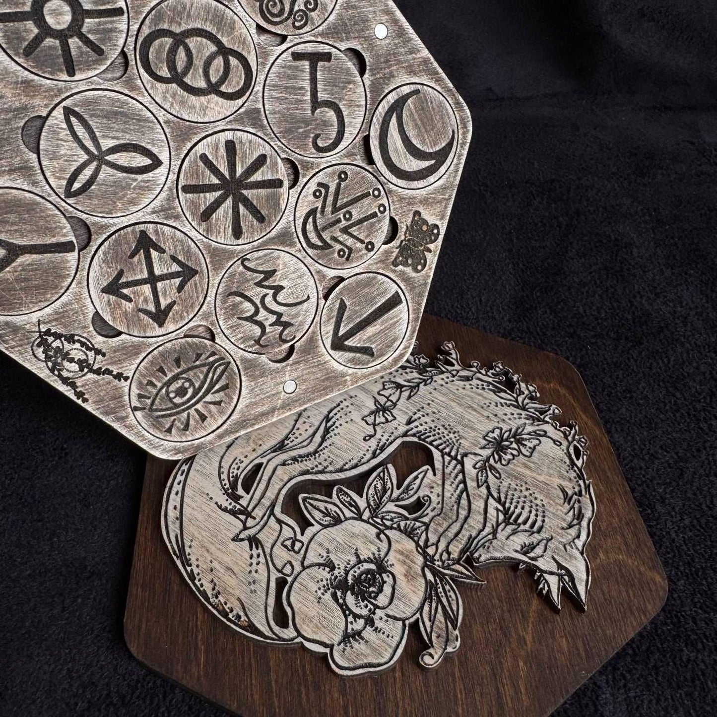 a wooden board with various symbols and designs carved into it, including a fox and other intricate patterns.