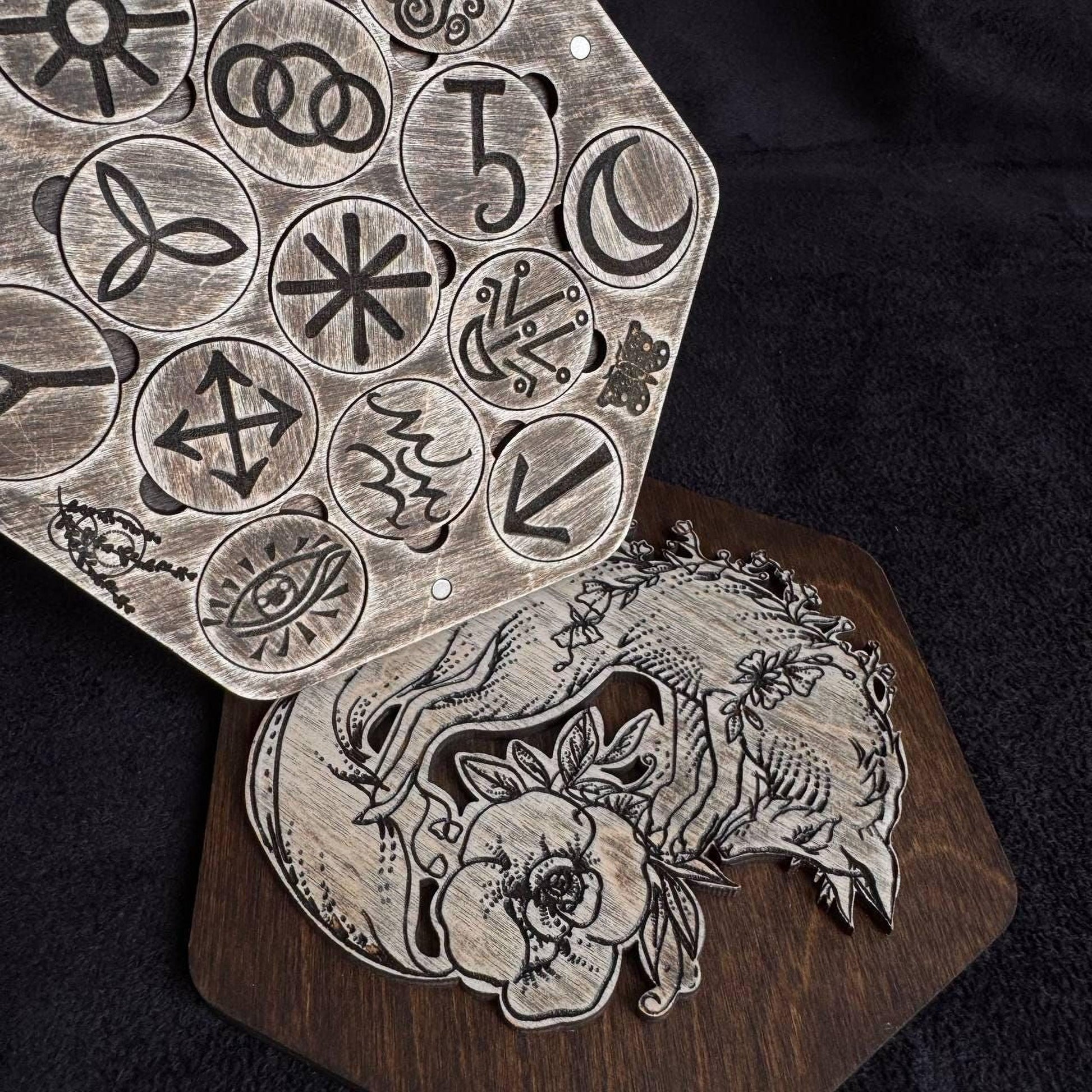 a wooden board with various symbols and designs carved into it, including a fox and other intricate patterns.