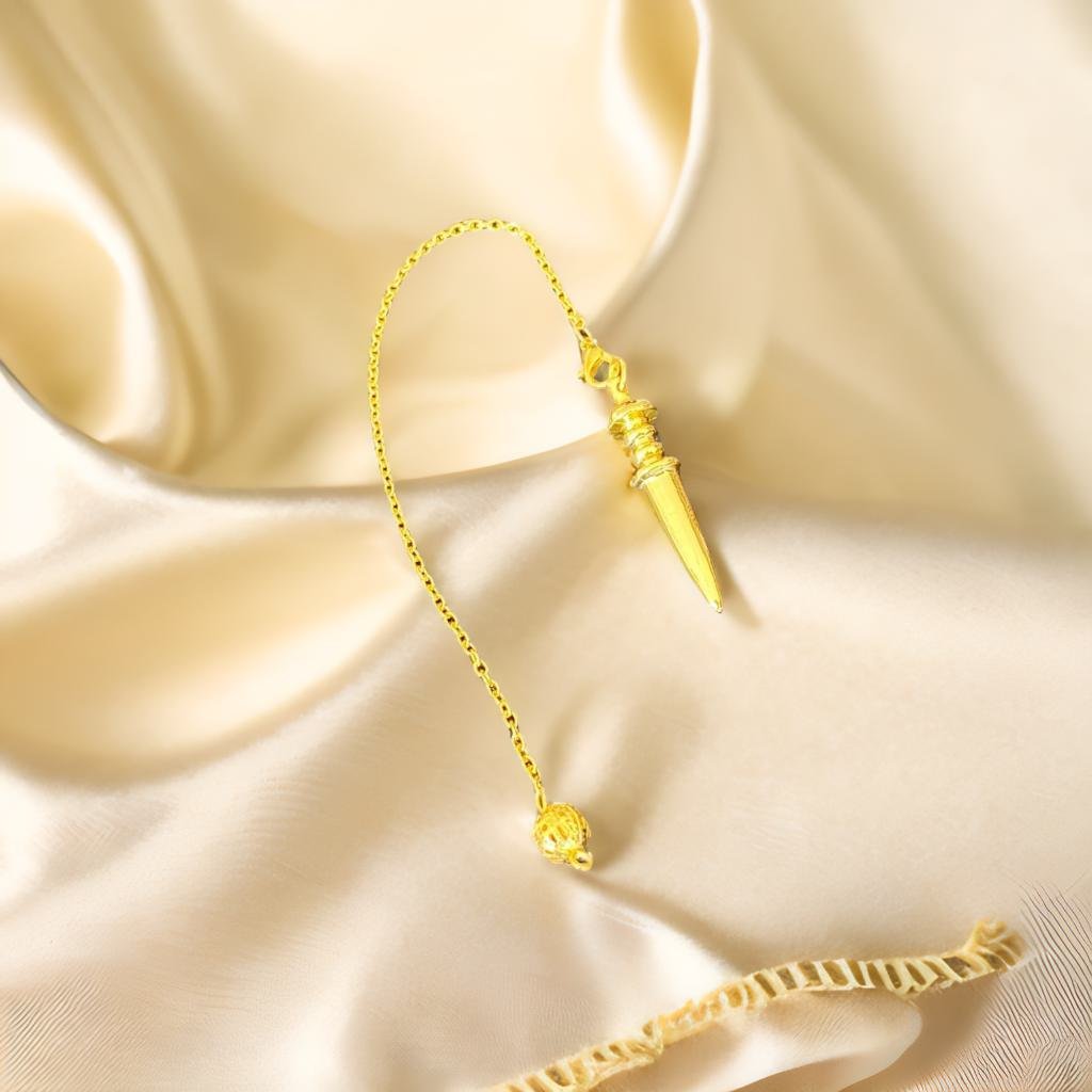 A gold pendulum with a small ball attached, resting on a white fabric surface.