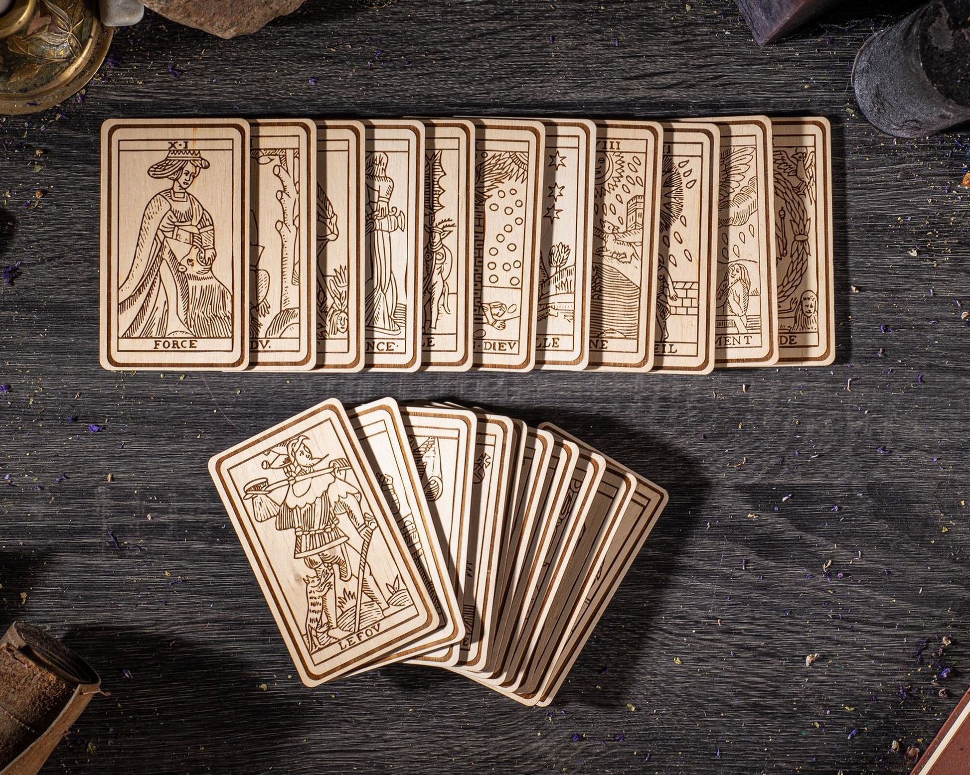 A collection of wooden tarot cards arranged on a dark wooden surface, with some cards folded and others standing upright.