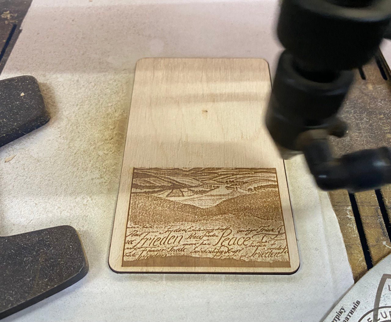 A wooden object with a printed image of a landscape on it, sitting on a workbench.