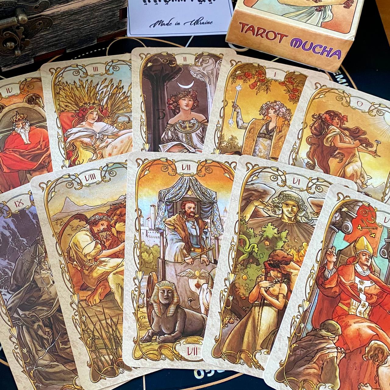 a collection of tarot cards arranged on a table, with a box of "Tarot Mucha" cards visible in the background.