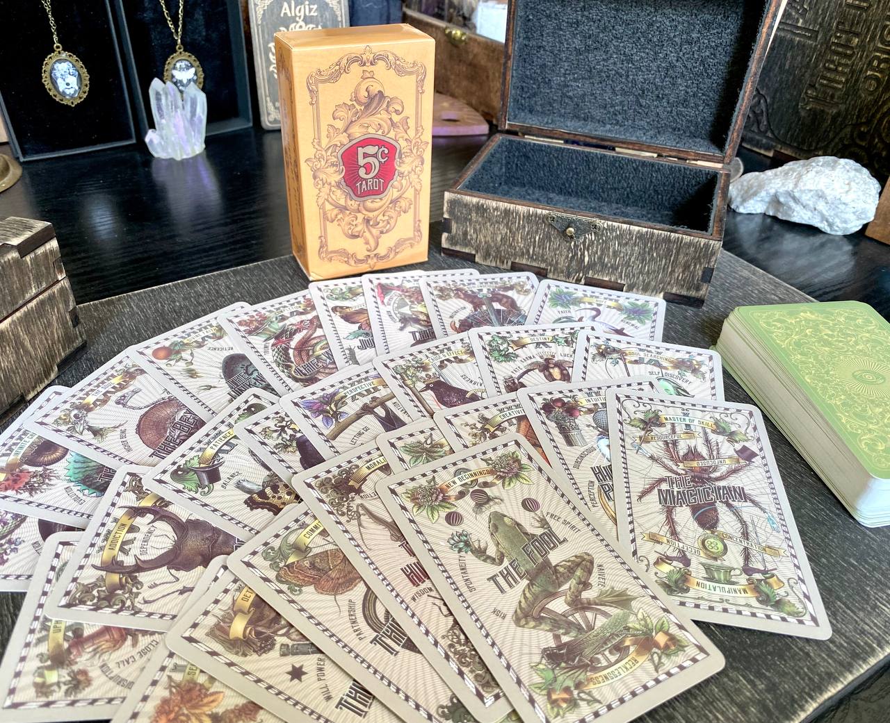 a collection of playing cards spread out on a table, along with a wooden box and some crystals.