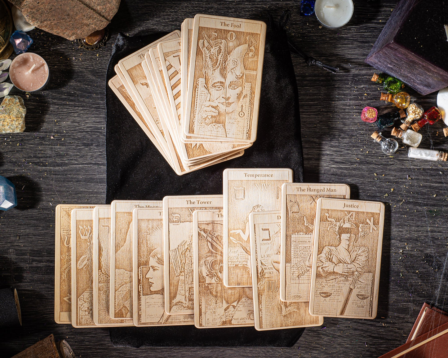 a collection of wooden tarot cards arranged on a wooden surface, with various objects such as candles, gemstones, and other items scattered around.