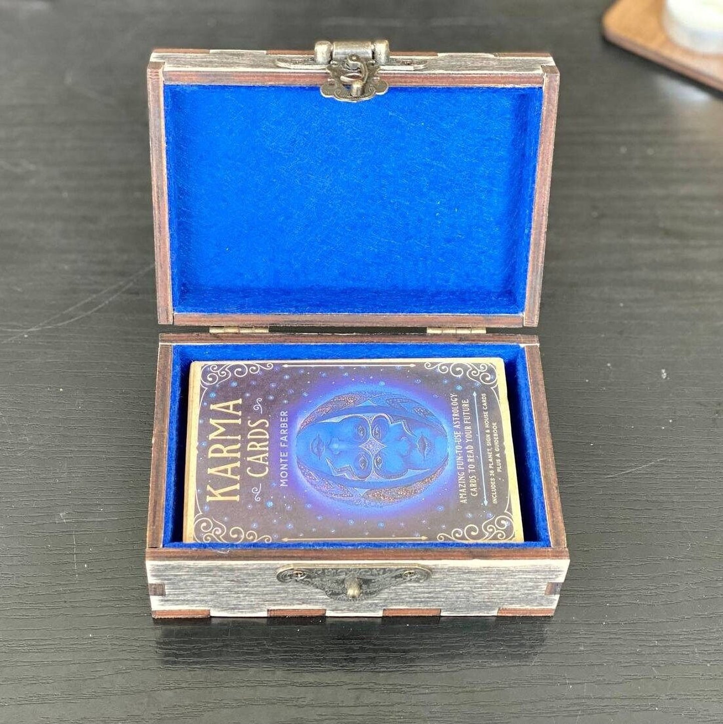 An open wooden box with a blue interior, containing a deck of playing cards.