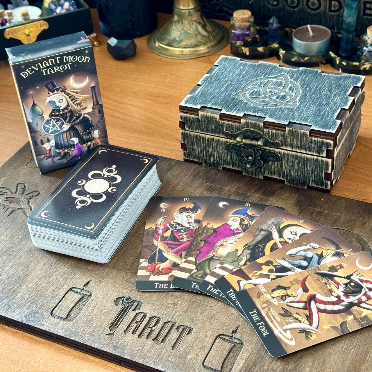 a tarot deck with a wooden board, a stack of cards, and a wooden box with a carved design.