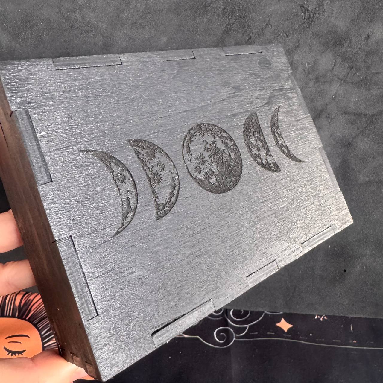 A wooden box with a design of the phases of the moon printed on it.