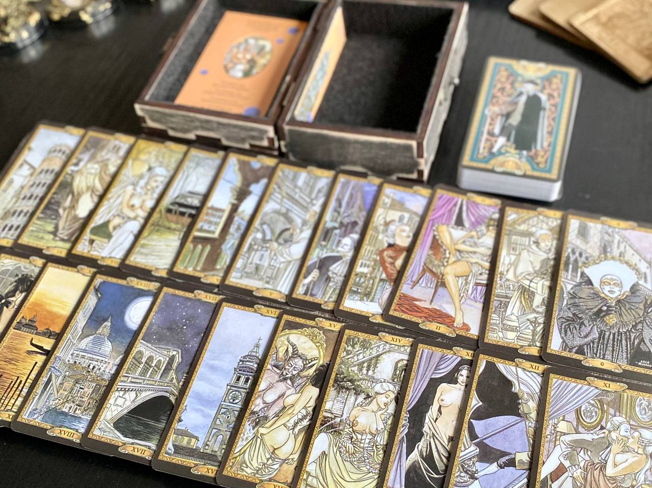a collection of tarot cards arranged on a table, with some cards in a box and others spread out.