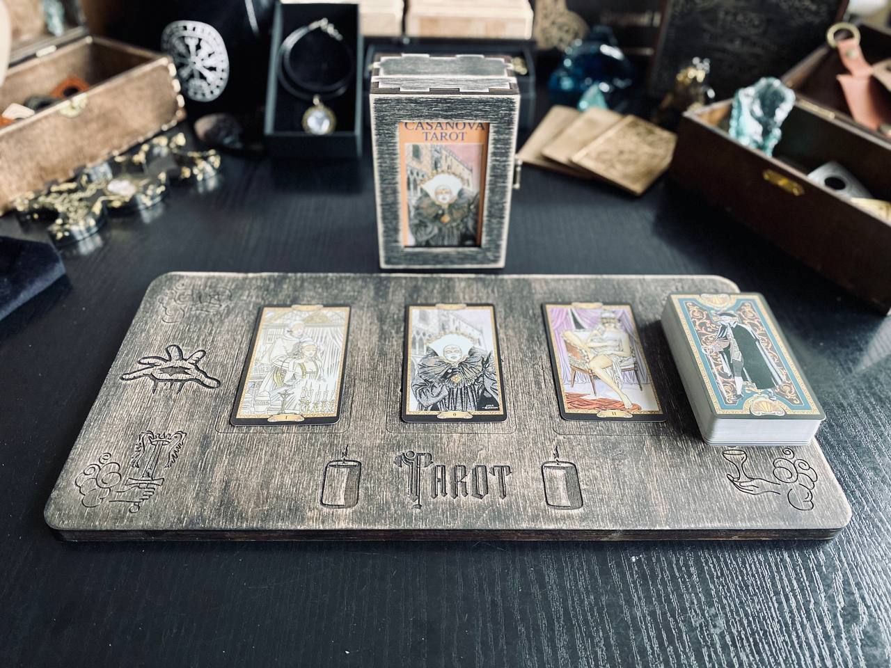 a tarot card reading setup on a wooden board, with three tarot cards arranged in a row. The board also has the word "TAROT" printed on it.