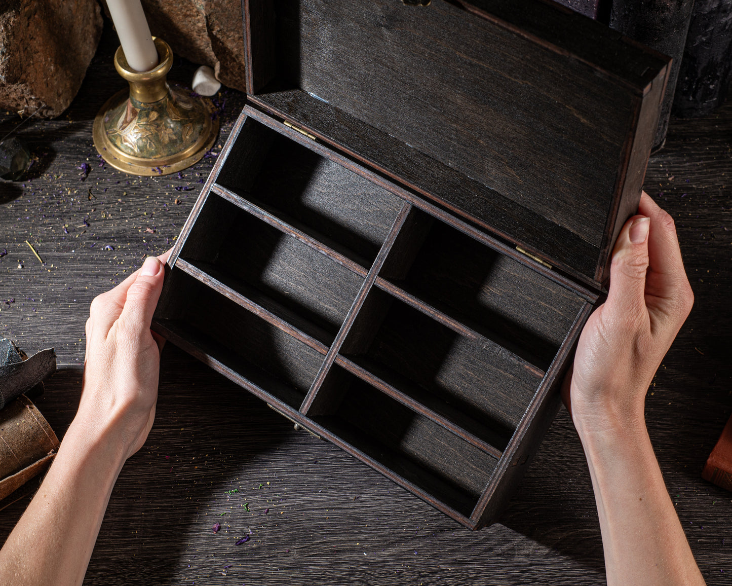 A person's hands are holding an open wooden box with six compartments, which appears to be a storage container.
