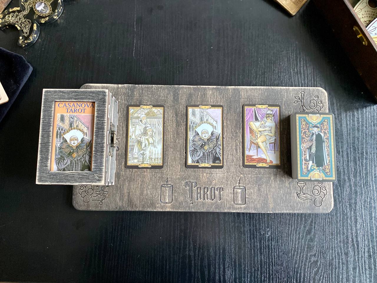 a wooden board with four tarot cards arranged on it, along with a small wooden box containing additional tarot cards.