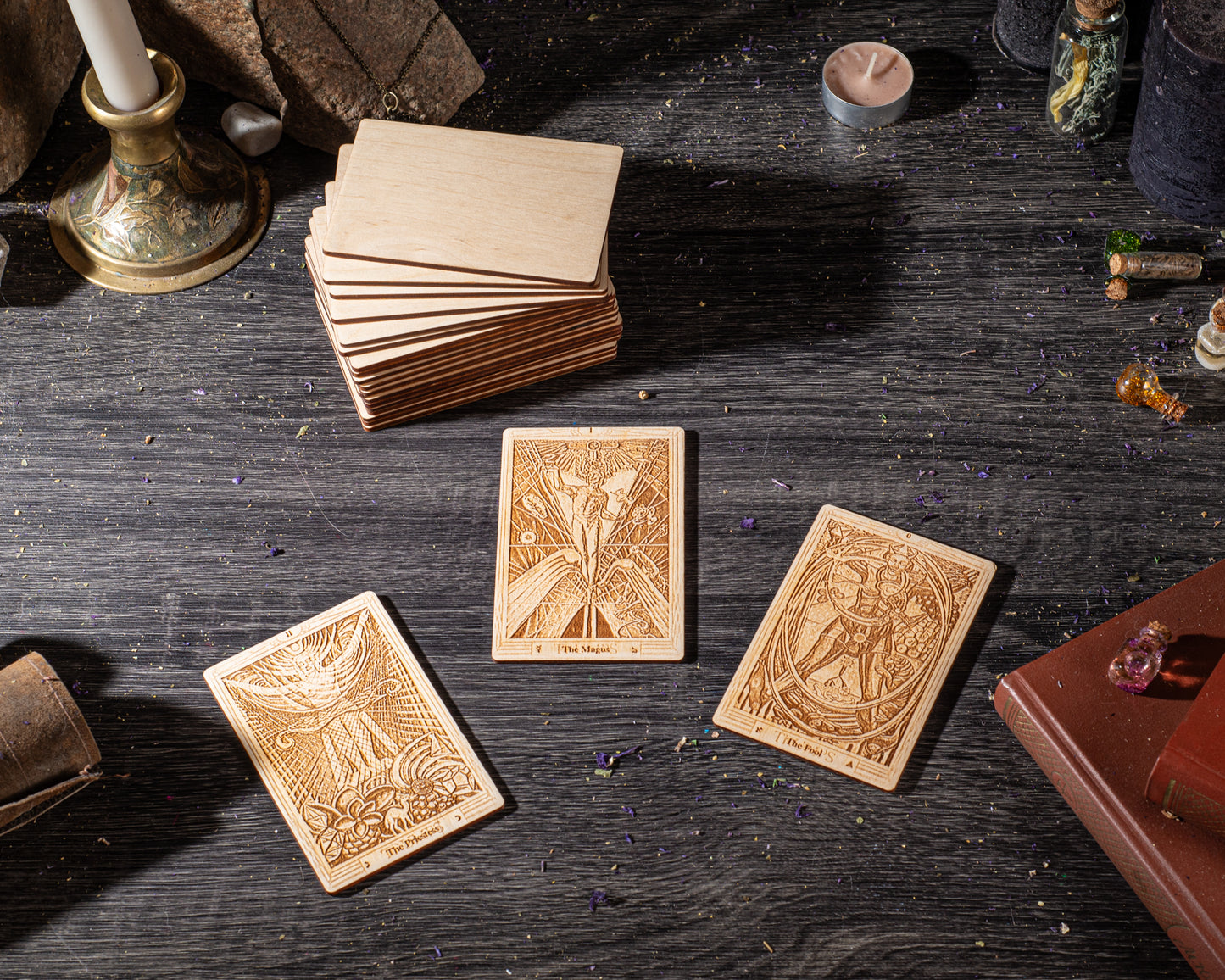 three wooden tarot cards arranged on a dark wooden surface, along with various other items such as candles, crystals, and books.