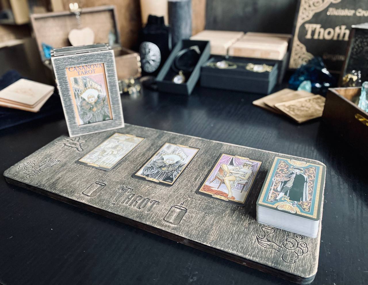 a wooden board with four tarot cards arranged on it, along with a small wooden box and various other items on a table.
