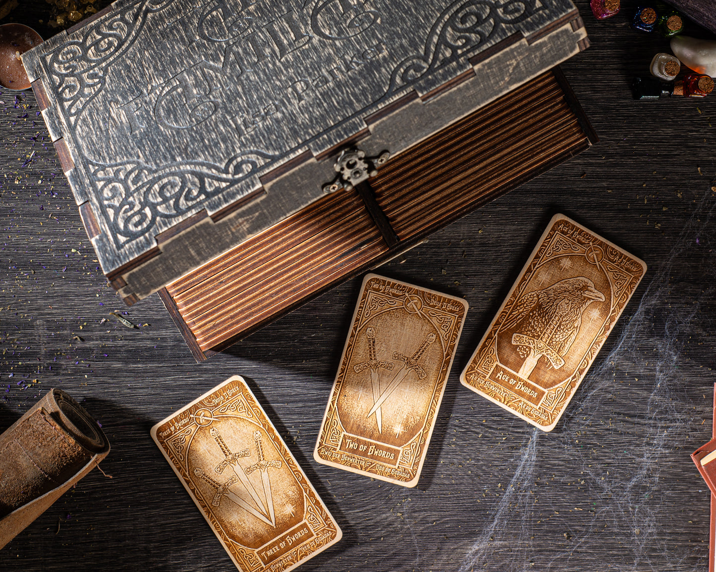 three wooden cards with intricate designs, placed on a dark wooden surface alongside a wooden box with a decorative lid.