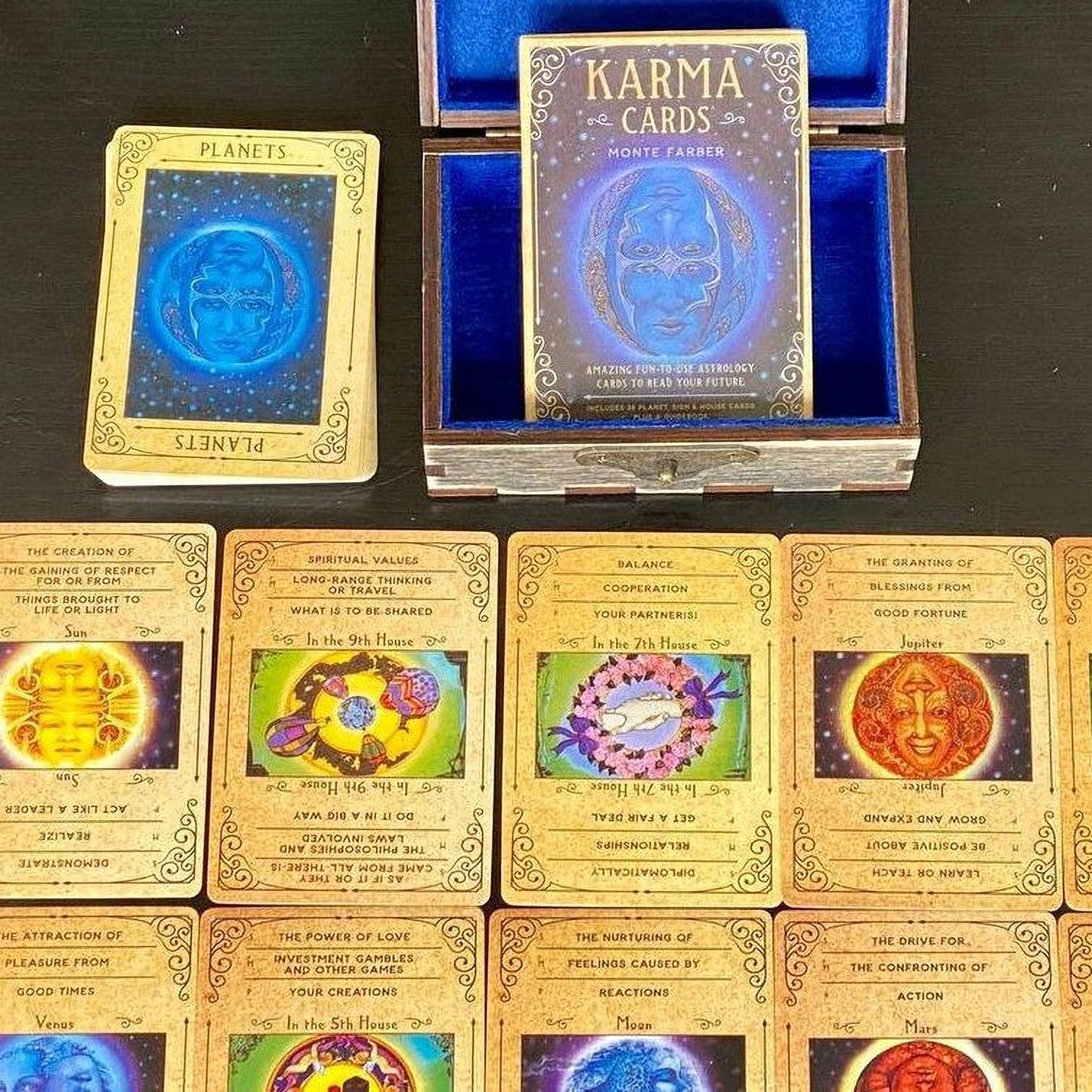 a collection of tarot cards and a box containing a deck of Karma Cards, arranged on a dark surface.