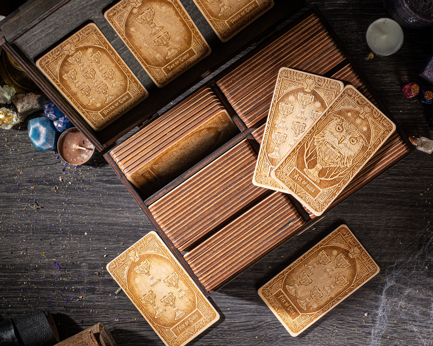 a collection of wooden tarot cards arranged on a wooden surface, with some cards placed in a wooden box.