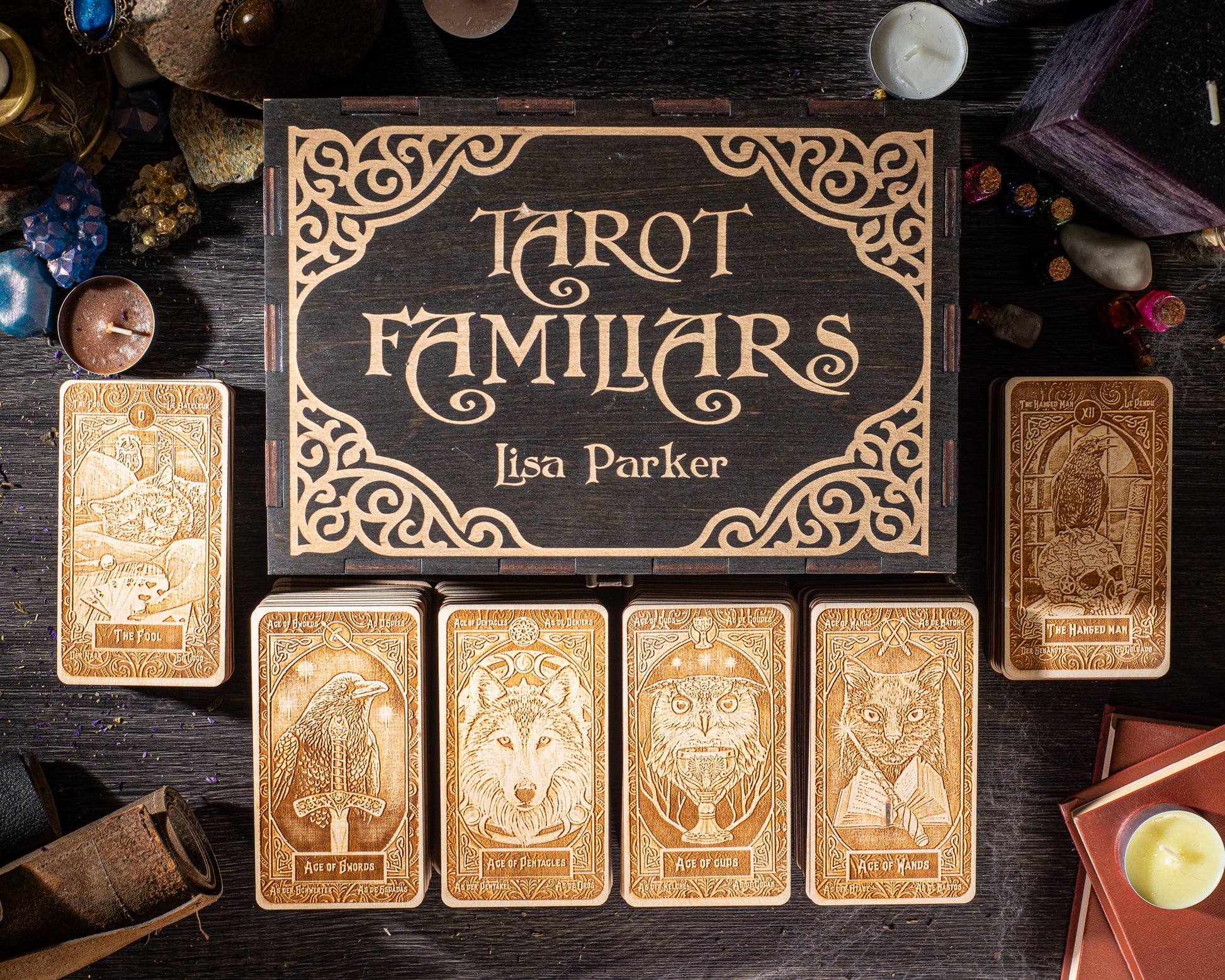 a collection of tarot cards and a wooden box with the title "Tarot Familiars" by Lisa Parker, arranged on a dark wooden surface.