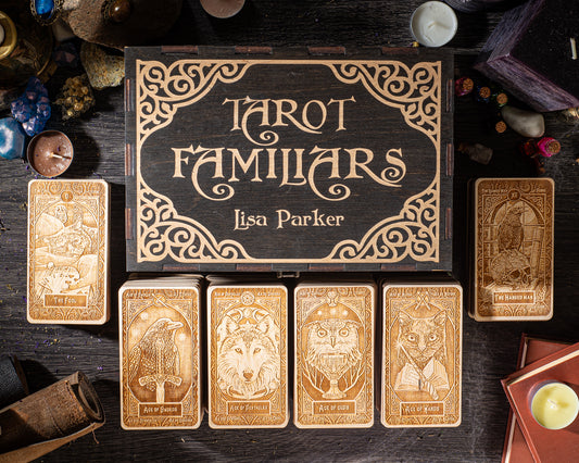 a collection of tarot cards and a wooden box with the title "Tarot Familiars" by Lisa Parker, arranged on a dark wooden surface.