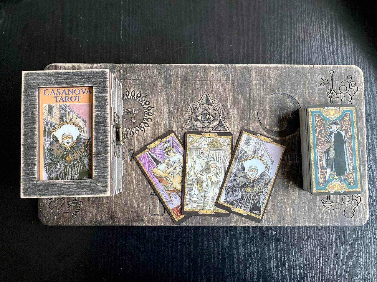 a tarot deck with a wooden box and a set of playing cards placed on a wooden surface.