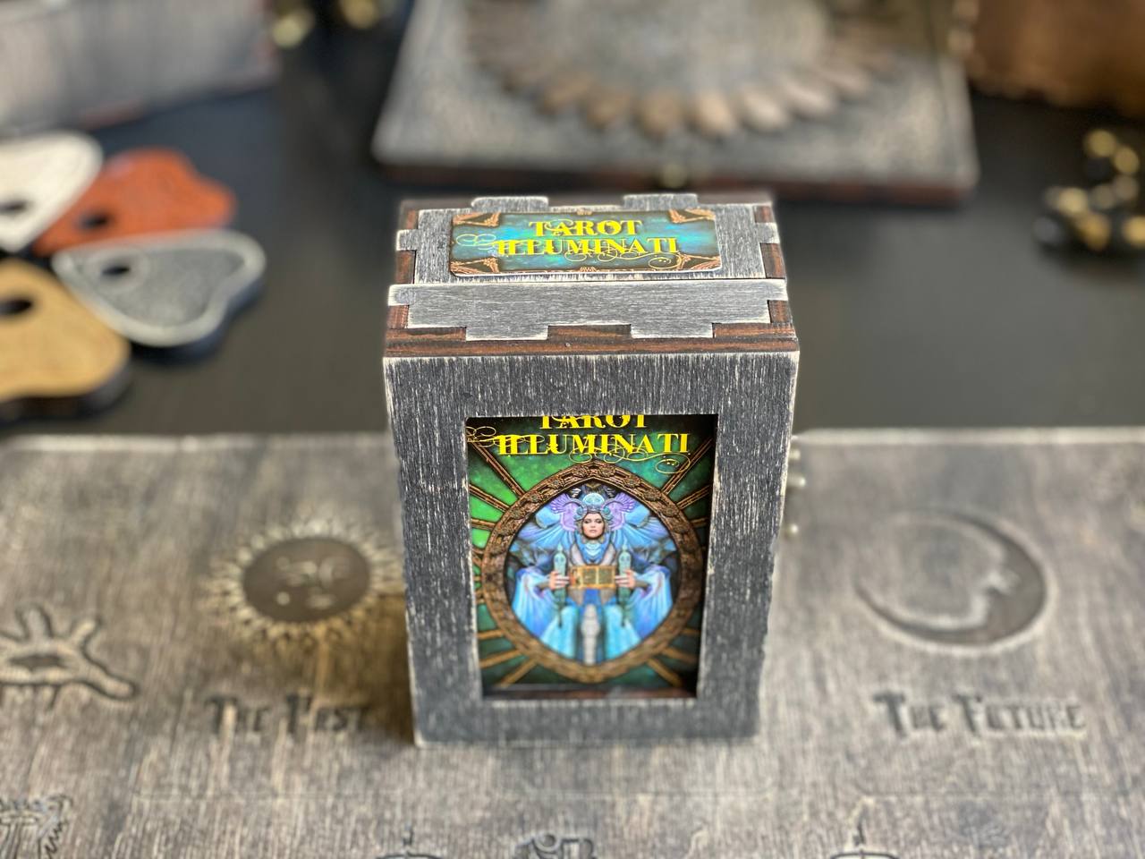 A wooden box with a colorful illustration of a figure, likely representing a tarot card, on a wooden surface.
