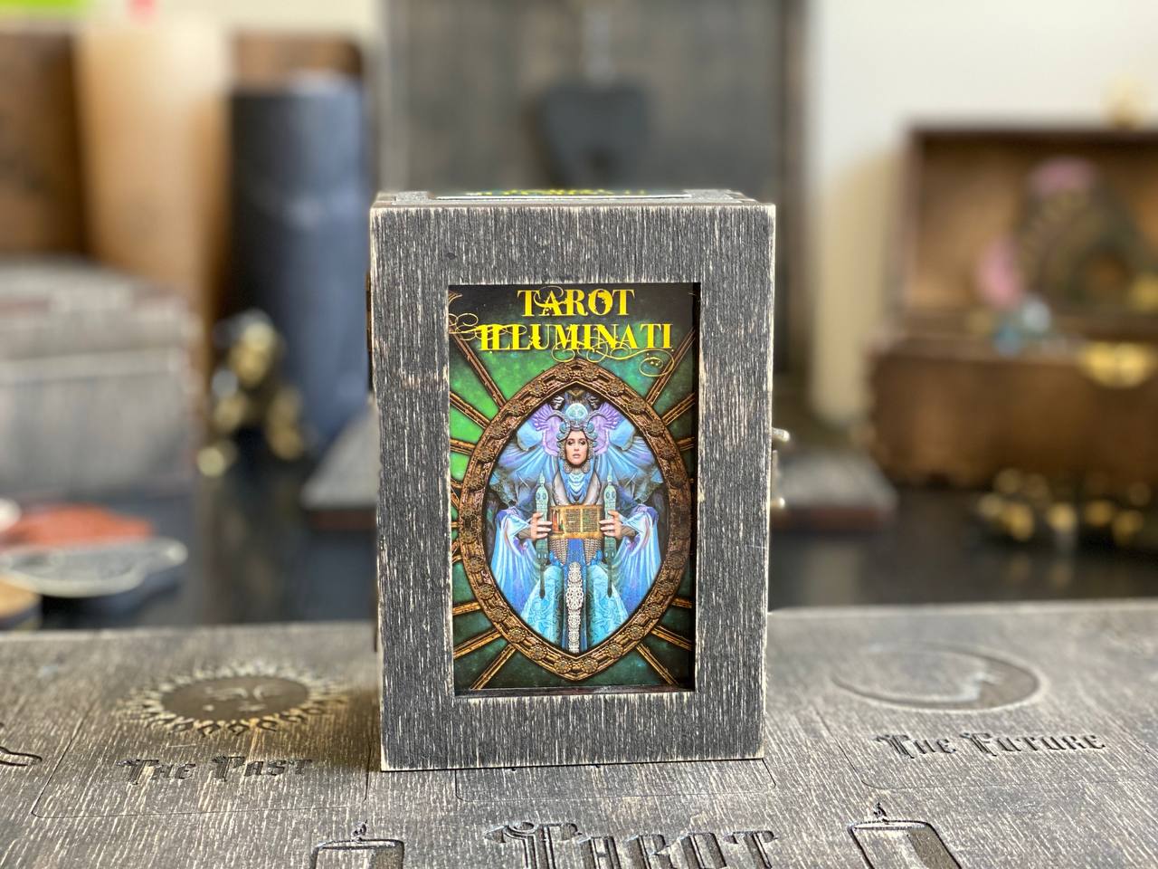A tarot deck box with a portrait of a woman inside, sitting on a wooden surface.