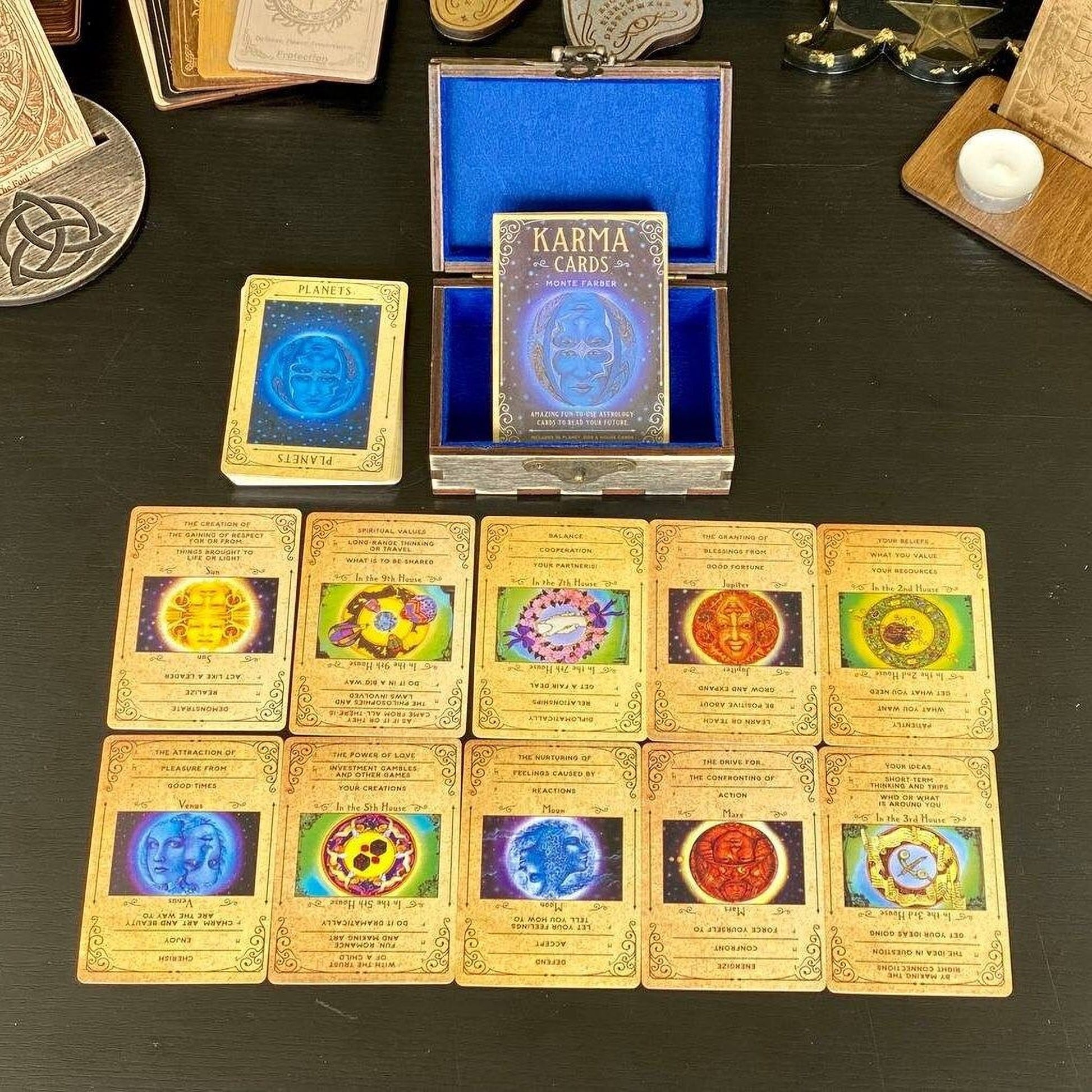 a collection of cards and a box containing the "KARMA CARDS" set, which is a tarot deck. The cards are arranged on a table, and the box is open, revealing the deck inside.