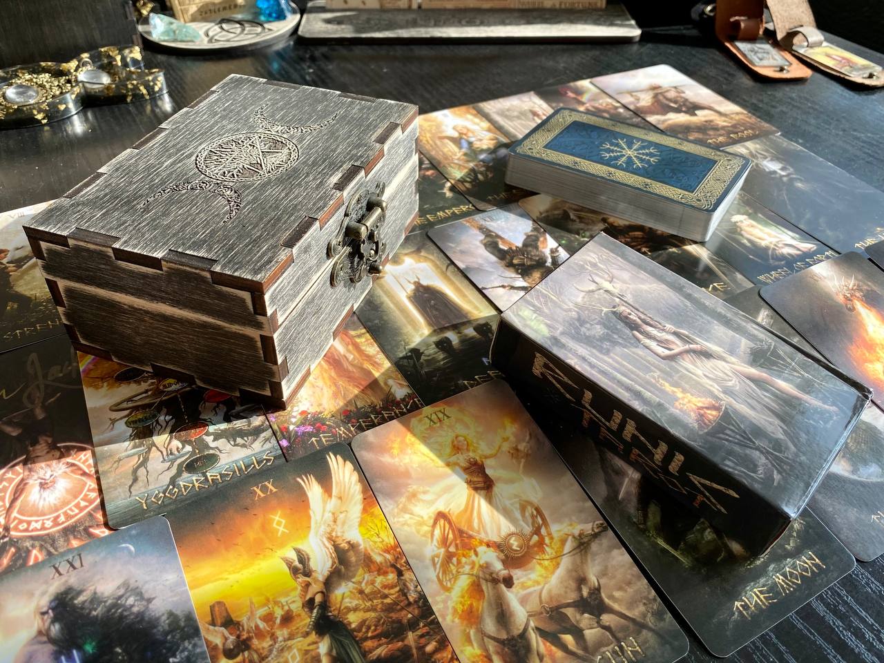 a collection of tarot cards and a wooden box with a dragon design, arranged on a table.