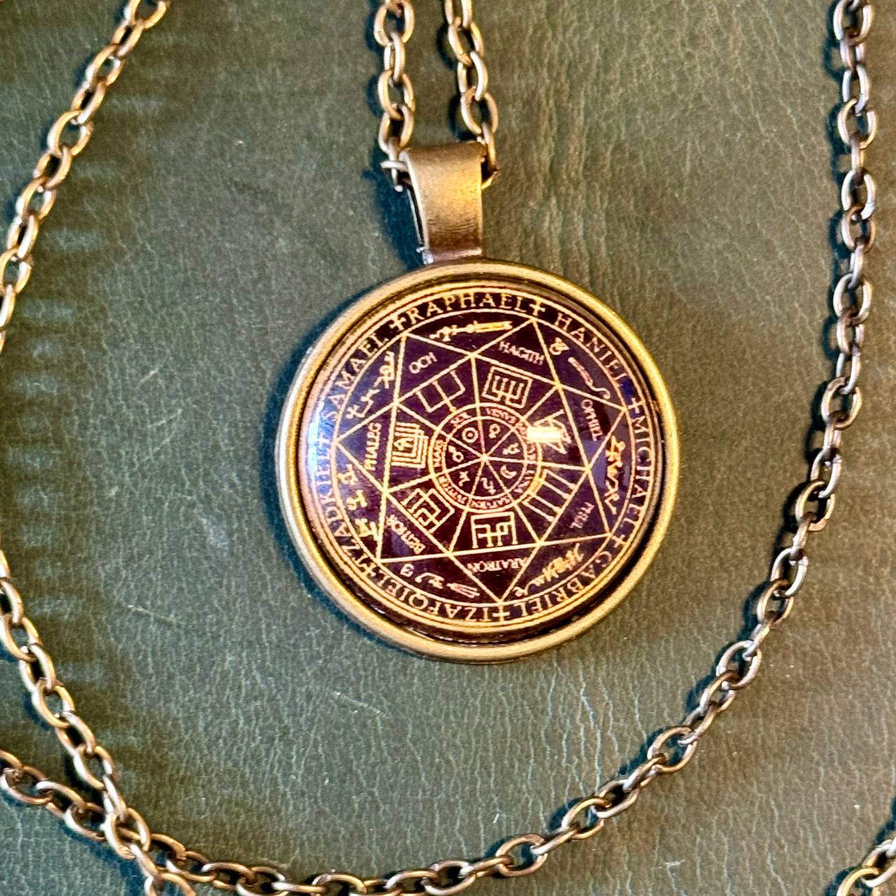 A pendant necklace with a circular medallion featuring a complex design and text.