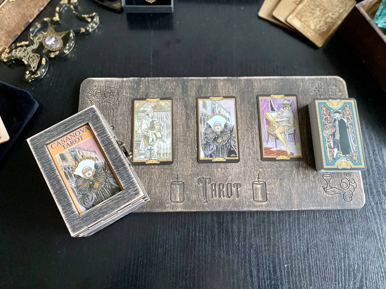 a collection of tarot cards arranged on a wooden board, with a small wooden box containing additional cards.