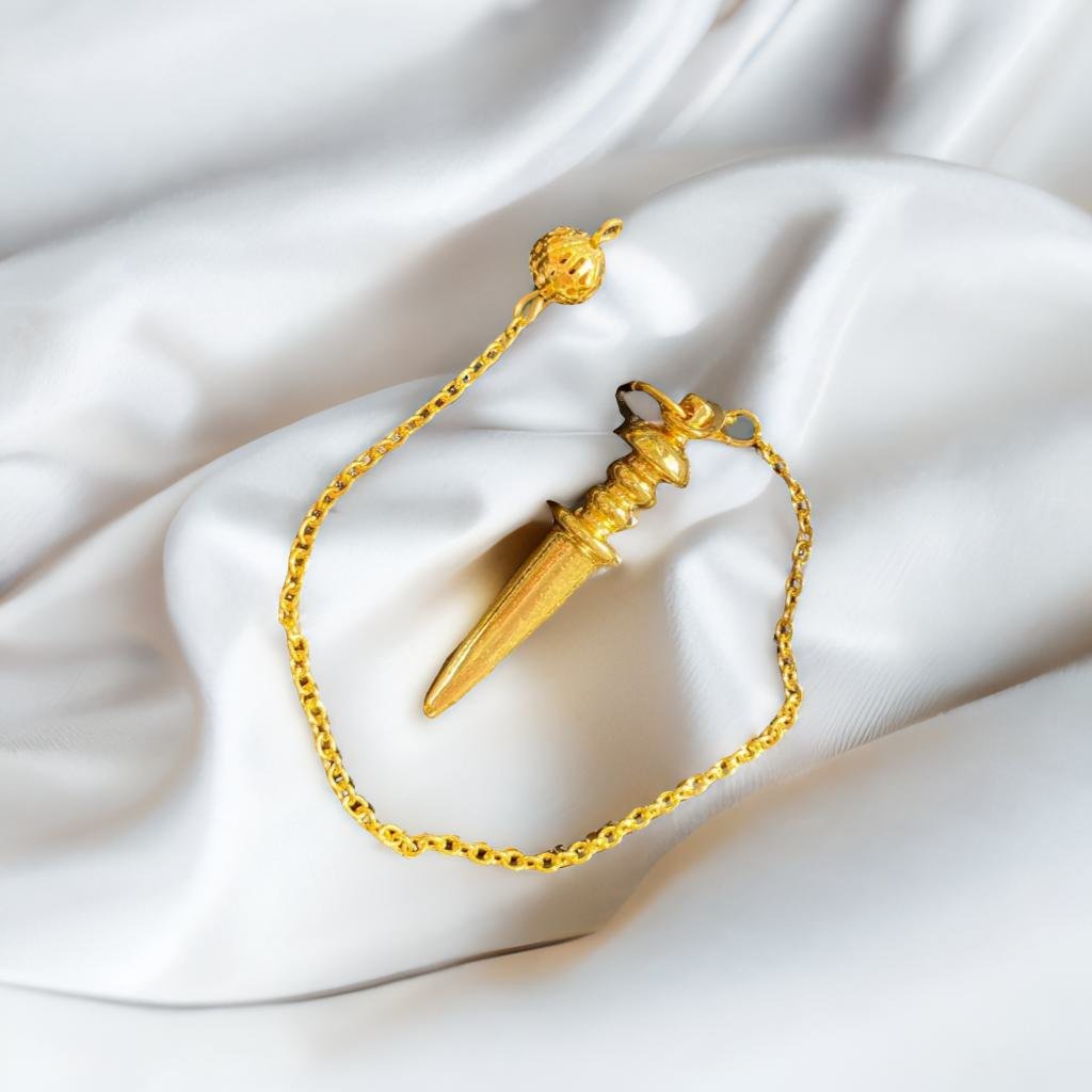 A gold pendant with a pointed design is displayed on a white fabric background.