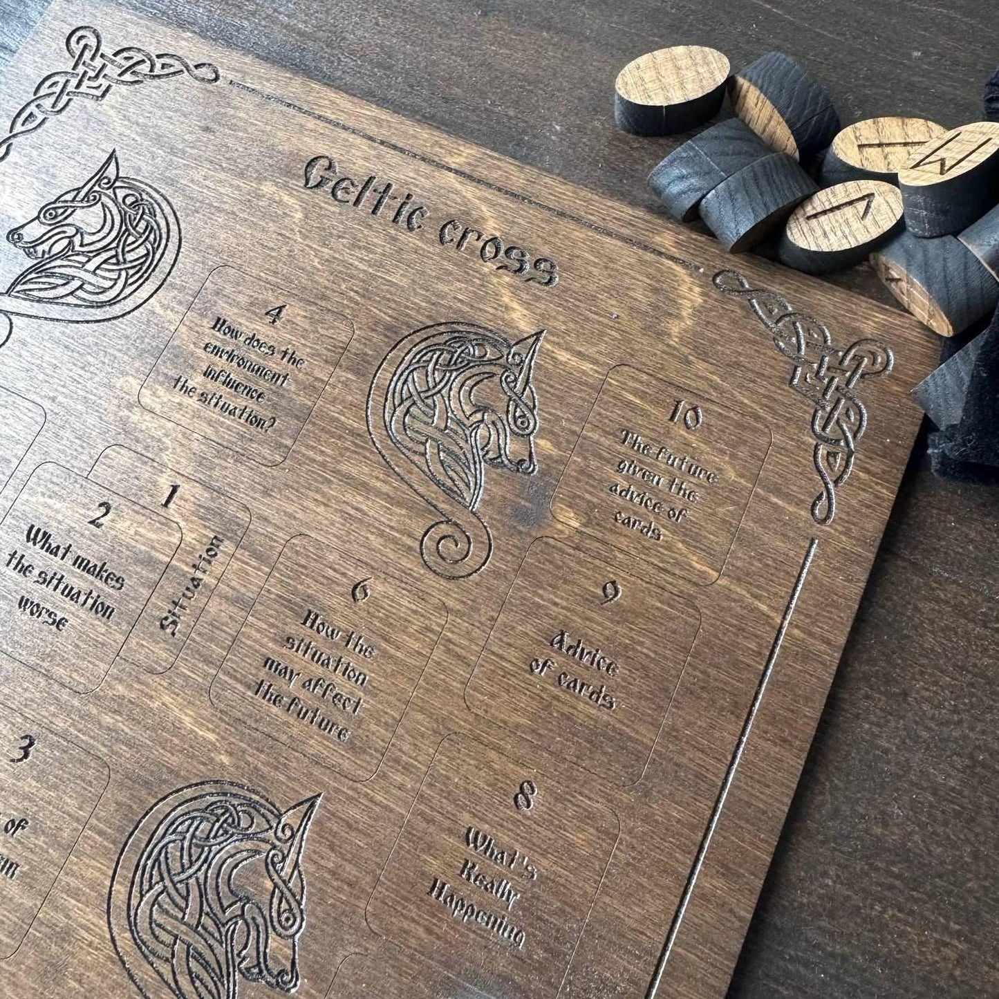a wooden board with various carved designs and text, including a Celtic cross, and some wooden pieces scattered around it.