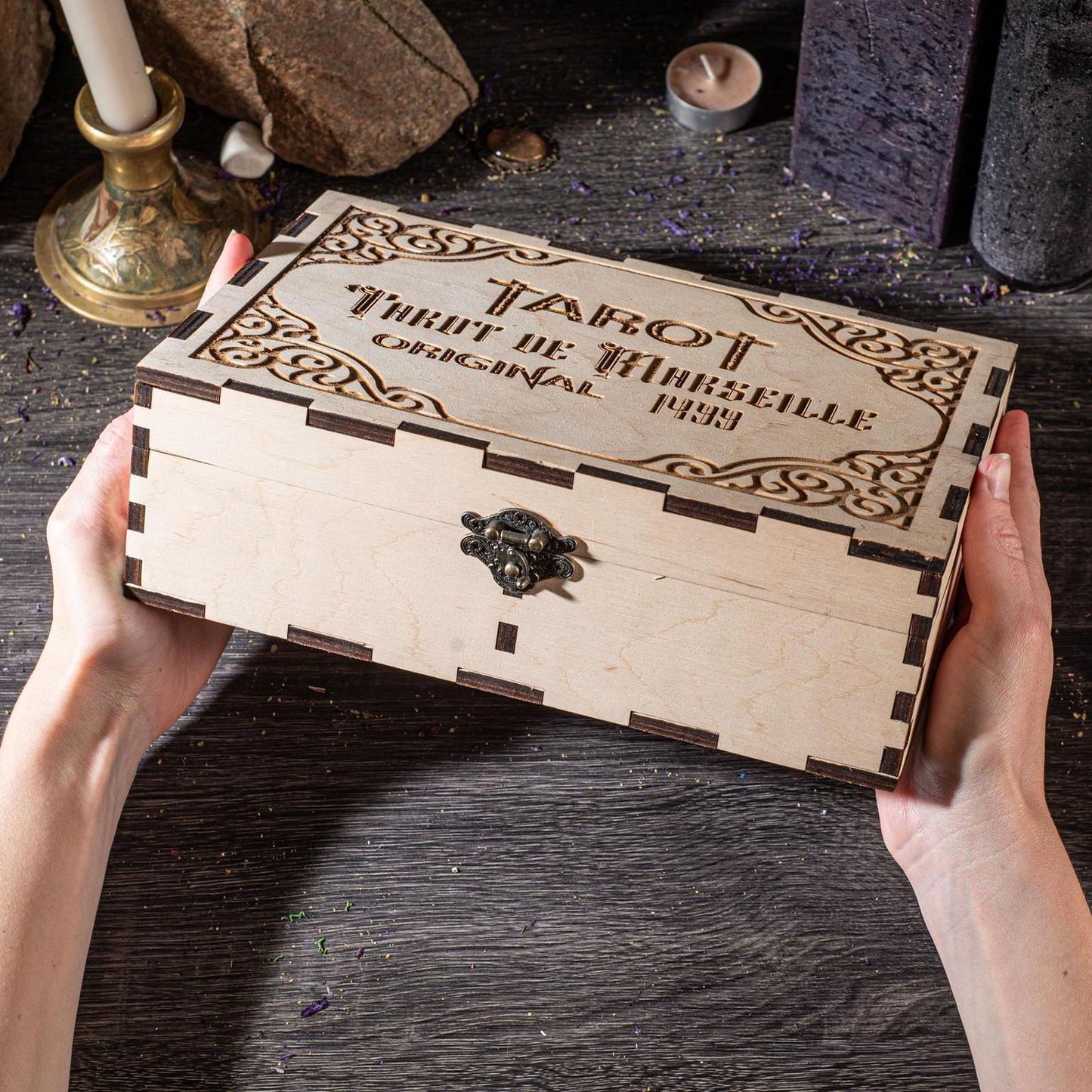 A person's hands are holding a wooden box with the text "TAROT" and "ORIGINAL" engraved on it, along with a key-like object.