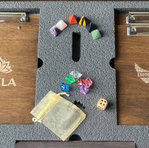 a wooden board with various items on it, including a small bag, a dice, and several colorful gemstones.