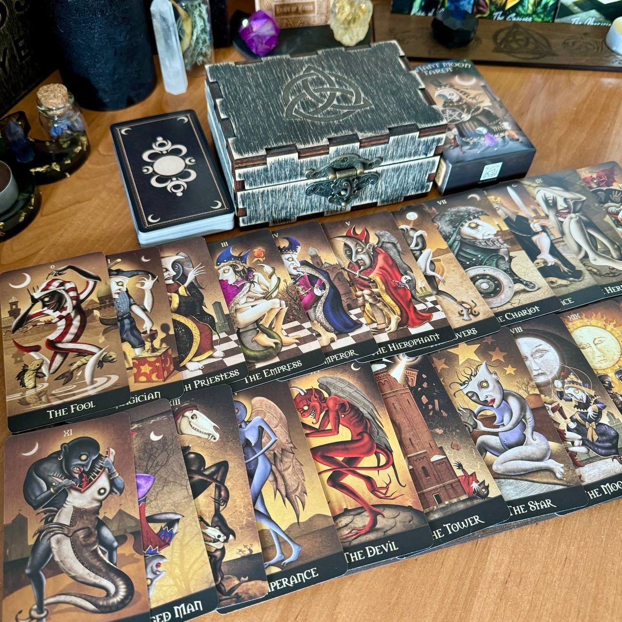a collection of tarot cards spread out on a wooden surface, along with a wooden box and various other items.