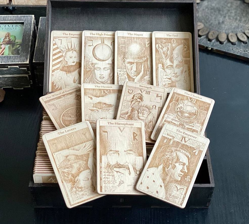 A collection of wooden tarot cards is displayed in a wooden box, with various designs and illustrations on the cards.