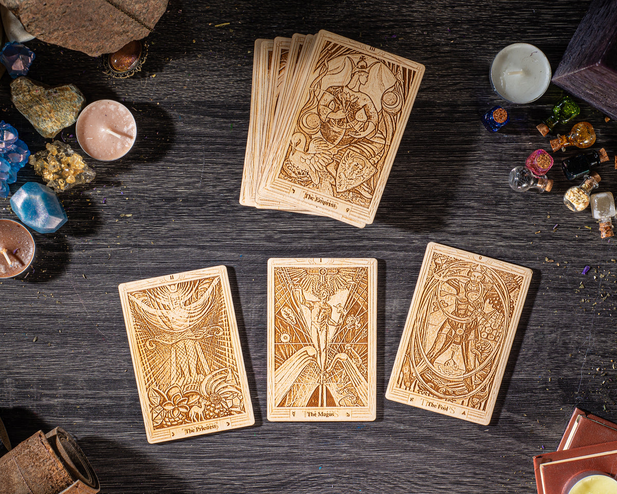 three wooden tarot cards arranged on a dark wooden surface, surrounded by various objects such as candles, gemstones, and other mystical items.