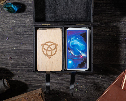 a wooden box with a crescent moon symbol on it, and a deck of playing cards inside the box, placed on a wooden surface.