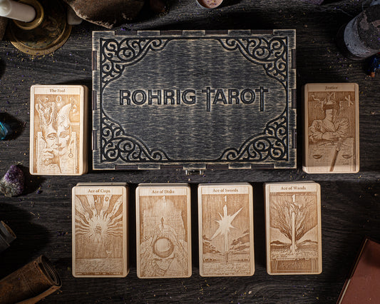 a collection of tarot cards arranged on a wooden surface, with a wooden box featuring the name "Rohrig Tarot" in the center.