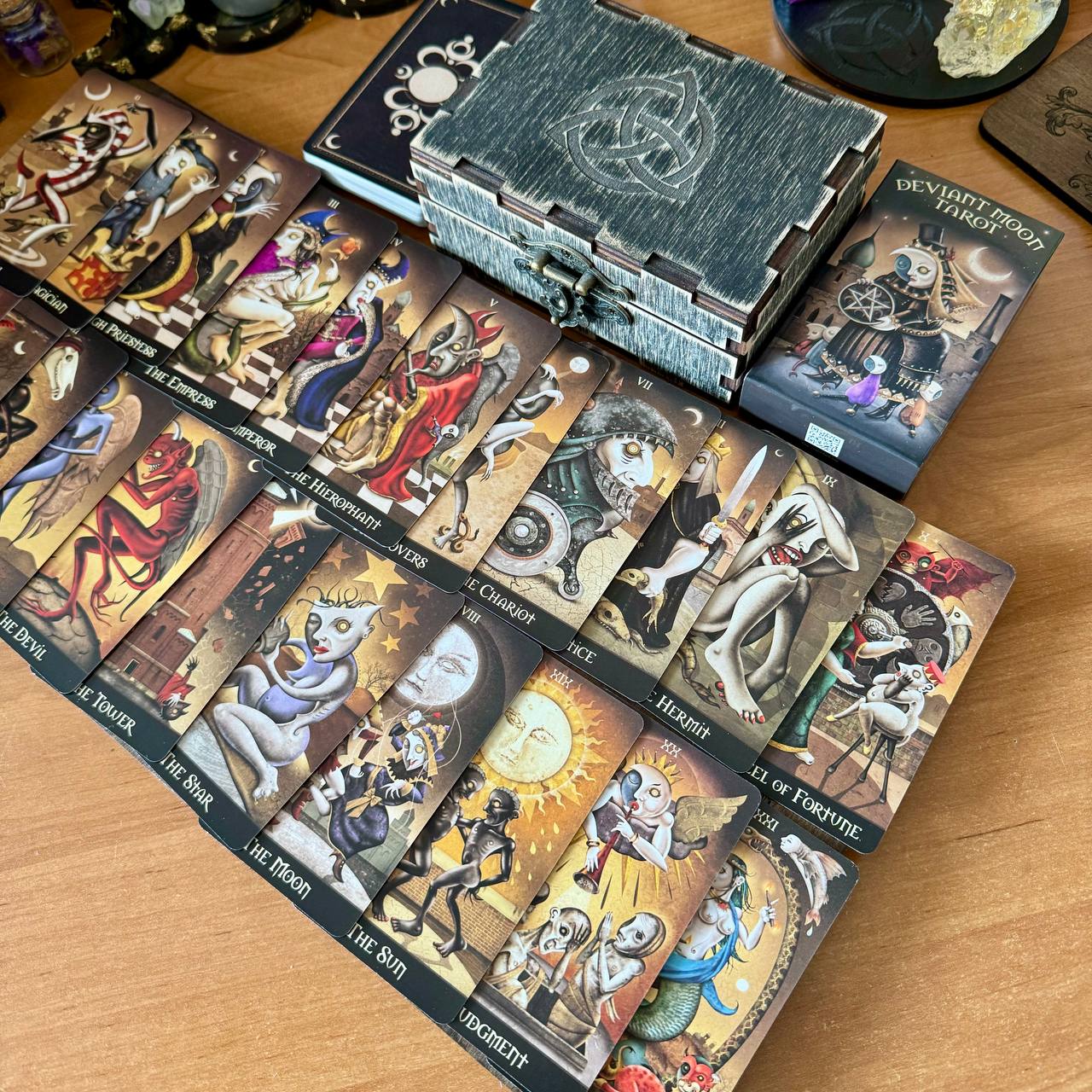 a collection of tarot cards and a deck of playing cards arranged on a wooden surface.