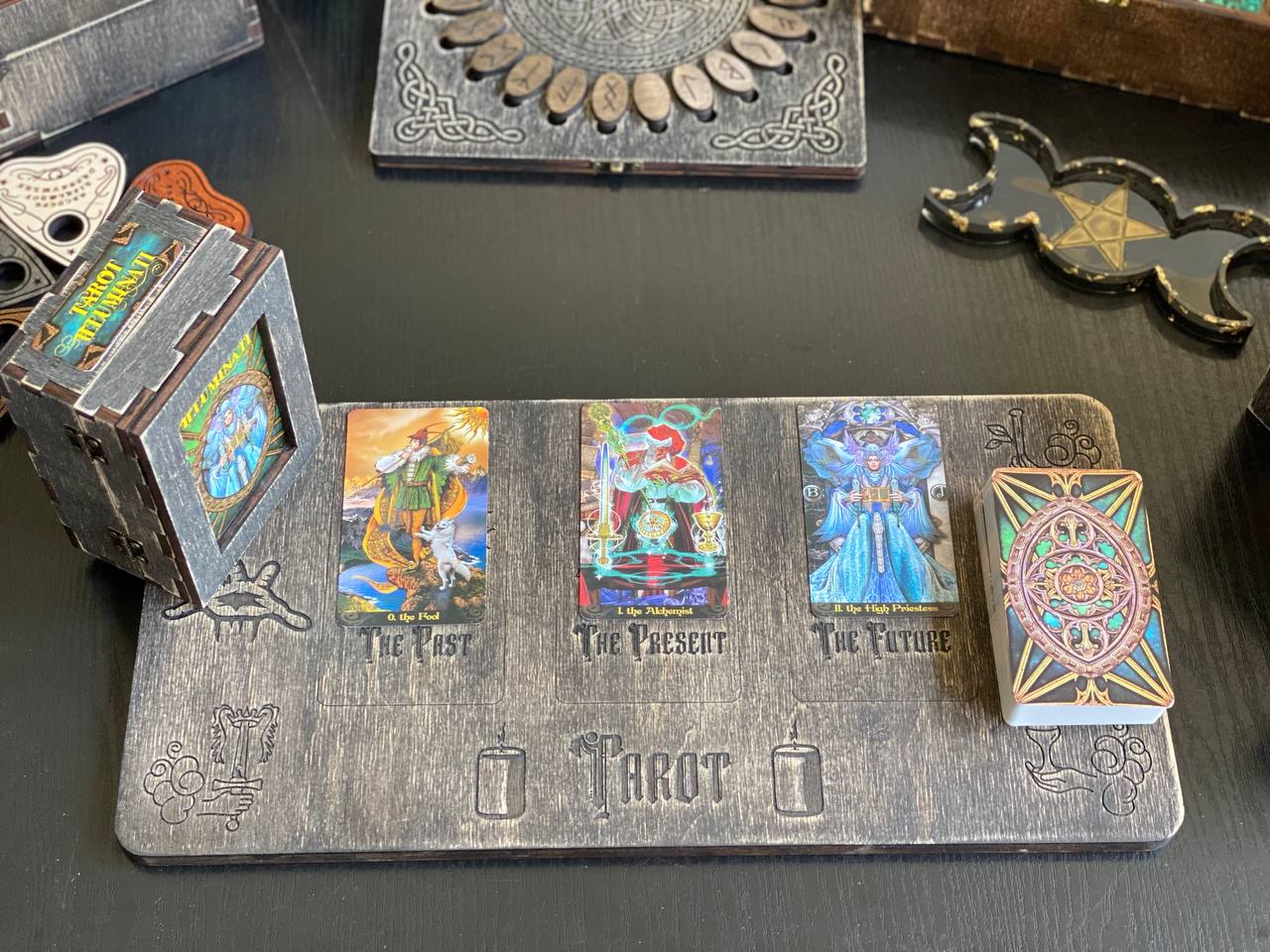 a tarot card reader's board with three tarot cards displayed on it, along with a small wooden box and some decorative items on a table.
