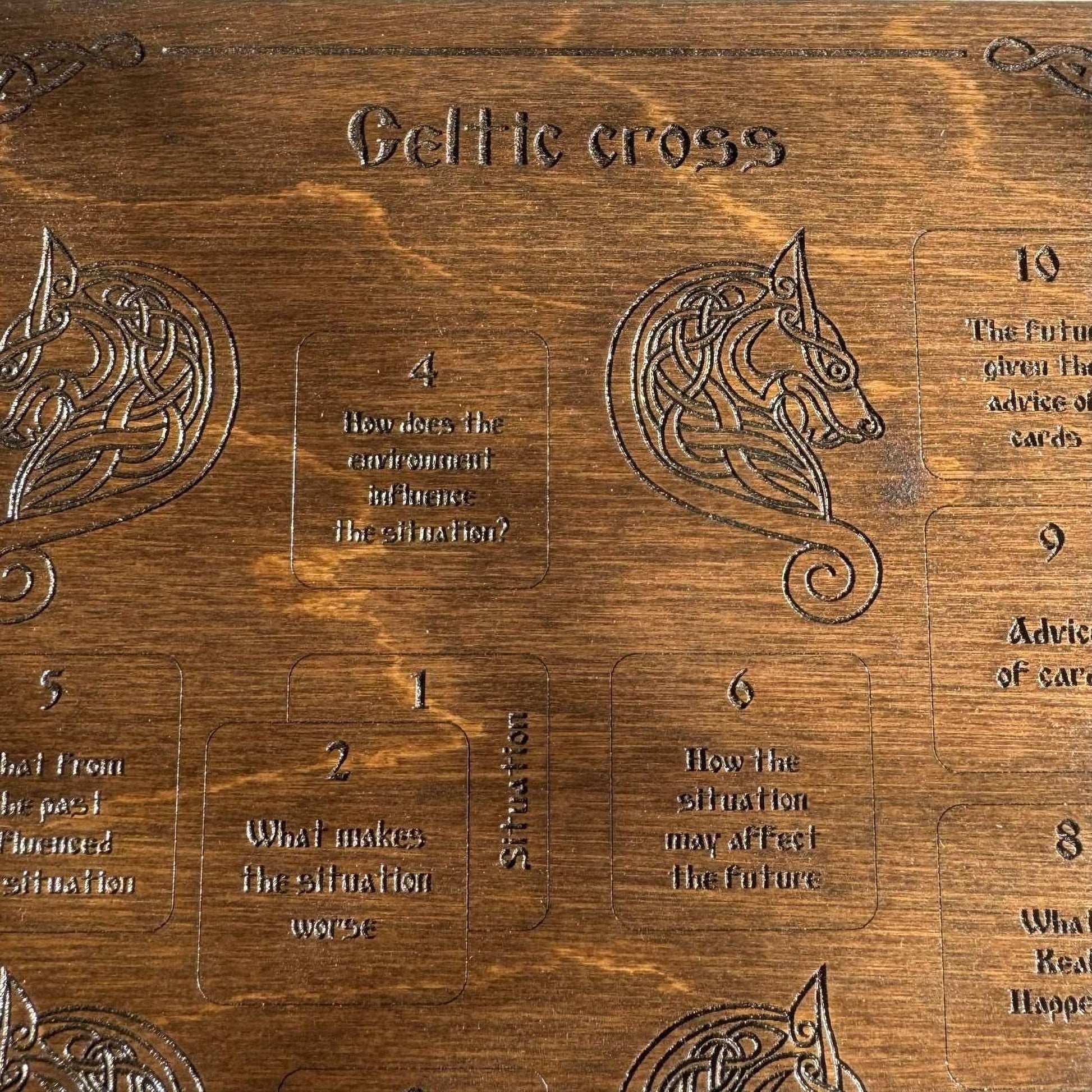 The image is a wooden board with various texts and symbols, including a Celtic cross design. The text appears to be in a foreign language, and the board is made of wood with a carved design.