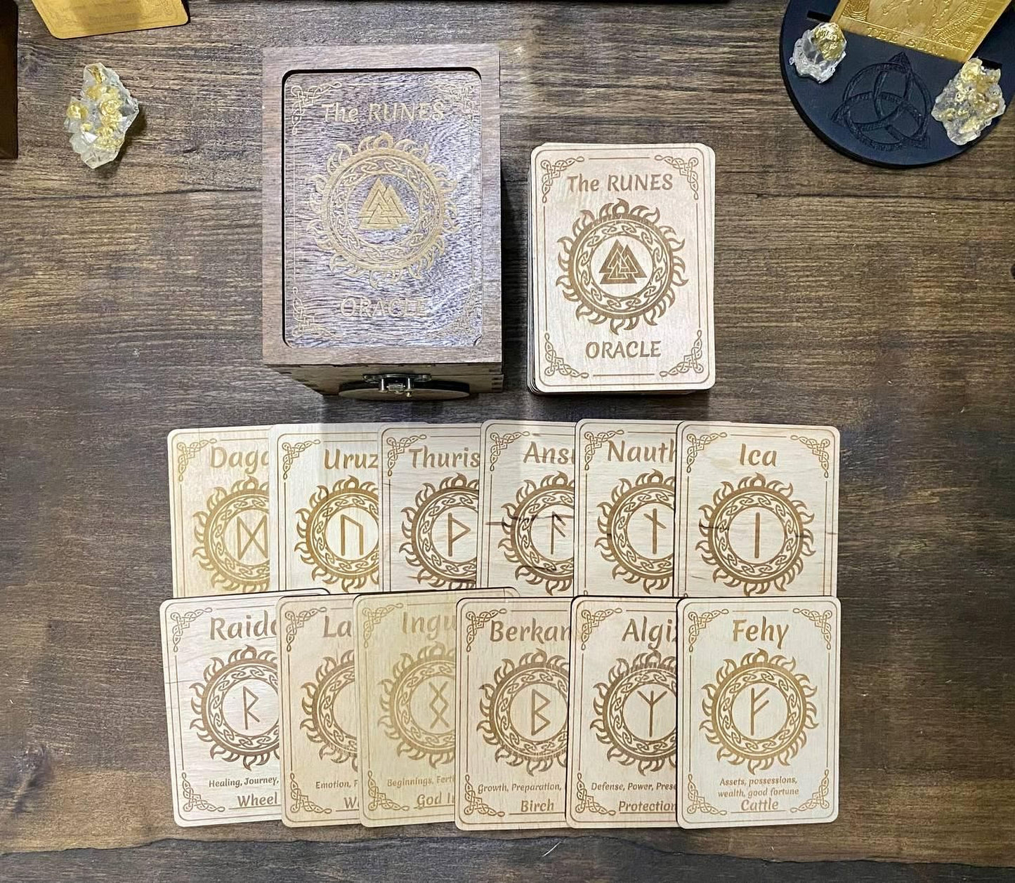 a collection of wooden cards with various symbols and text, arranged on a wooden surface. The cards appear to be part of a tarot deck or fortune teller's kit, with the cards labeled with names and symbols.