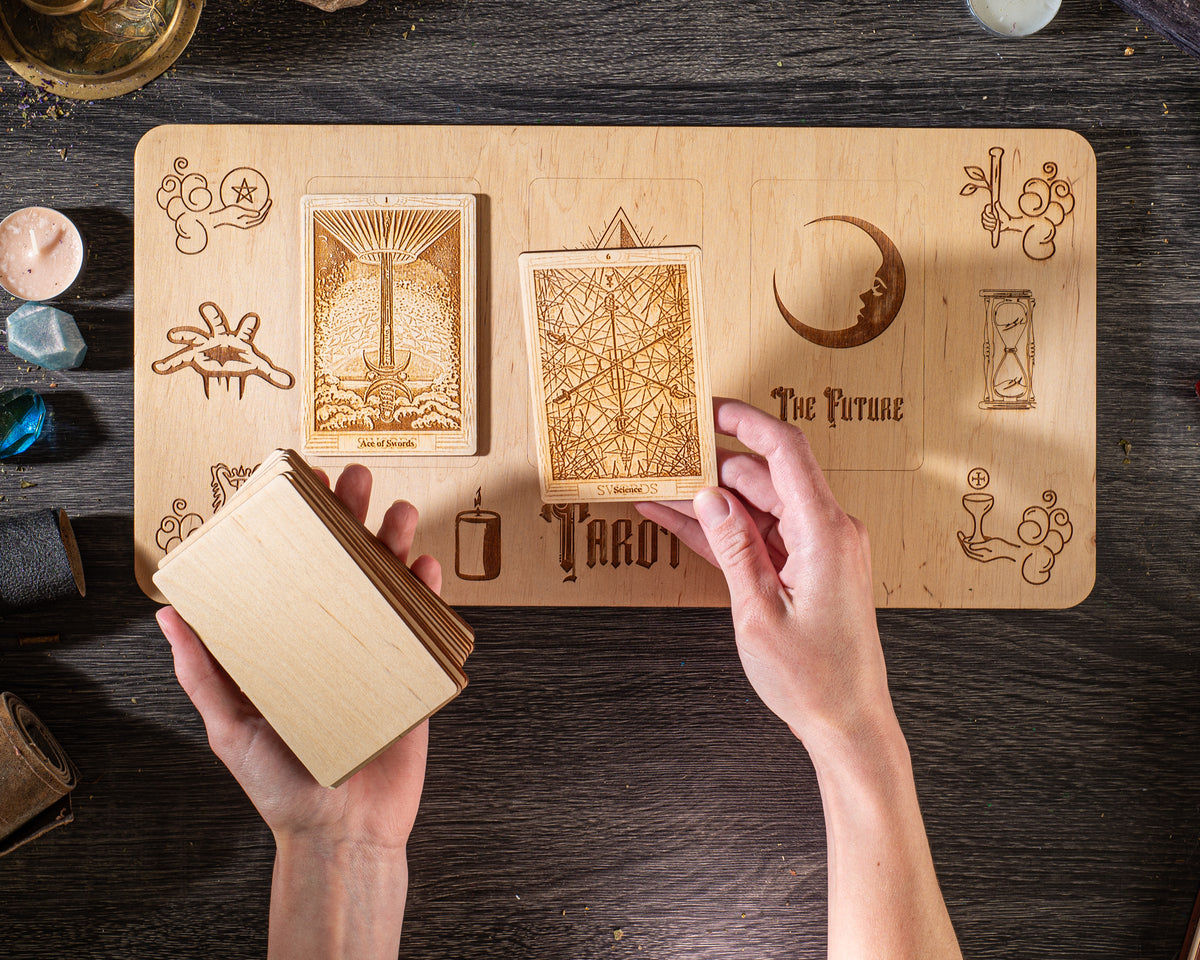 A person's hands are holding a stack of wooden cards with various designs and symbols on them, placed on a wooden surface.