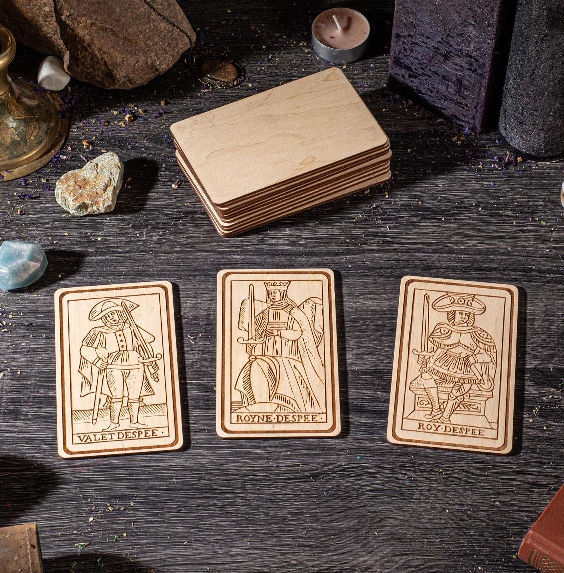 three wooden tarot cards with illustrations of characters, arranged on a wooden surface.