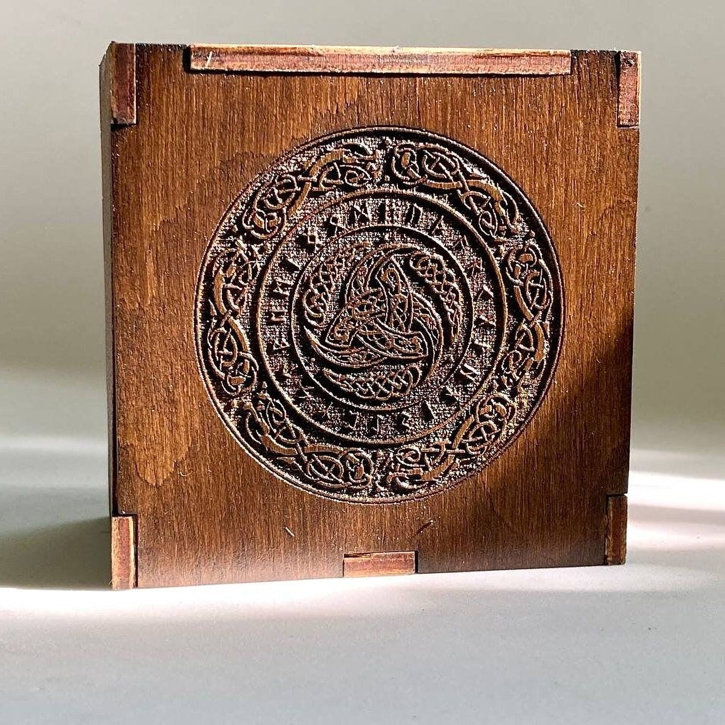 a wooden box with an intricate carved design on its surface.