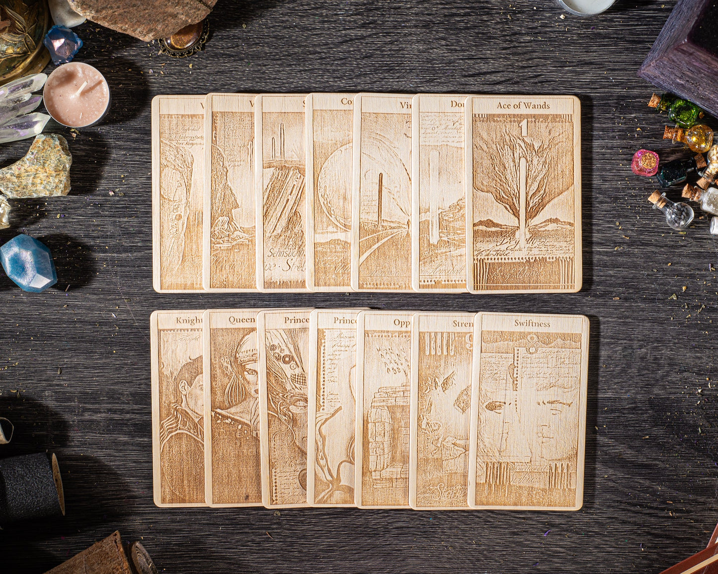 A collection of wooden tarot cards arranged on a dark wooden surface, with various objects such as gemstones, crystals, and other items scattered around them.