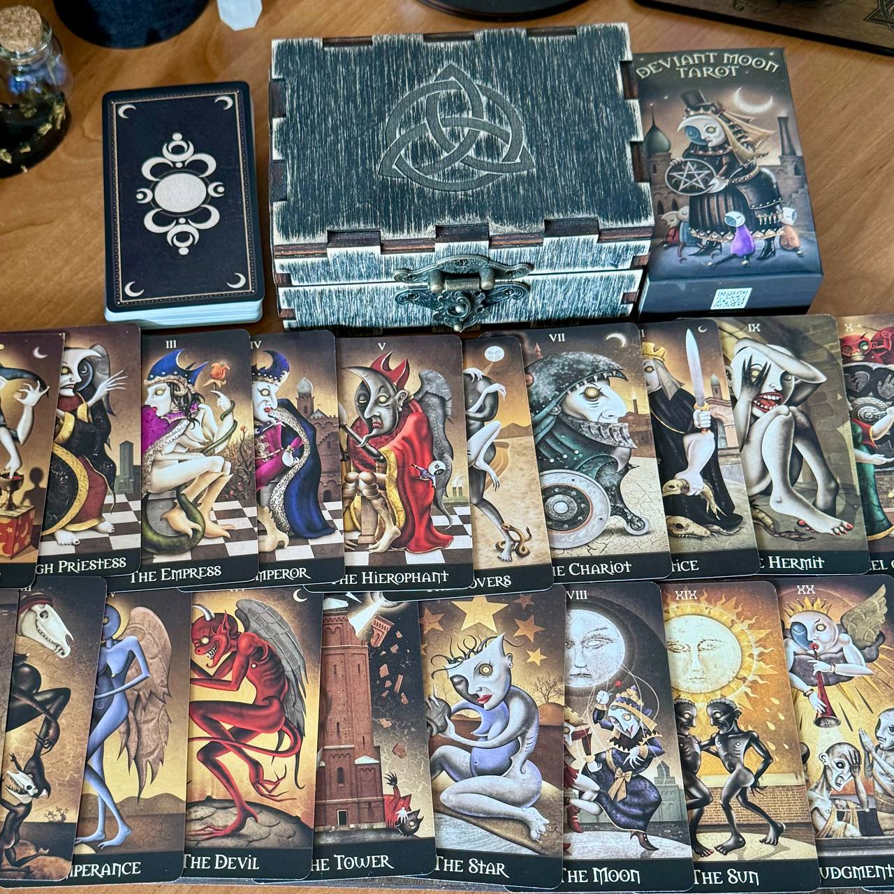 a collection of tarot cards arranged on a wooden surface, along with a wooden box containing additional tarot cards.