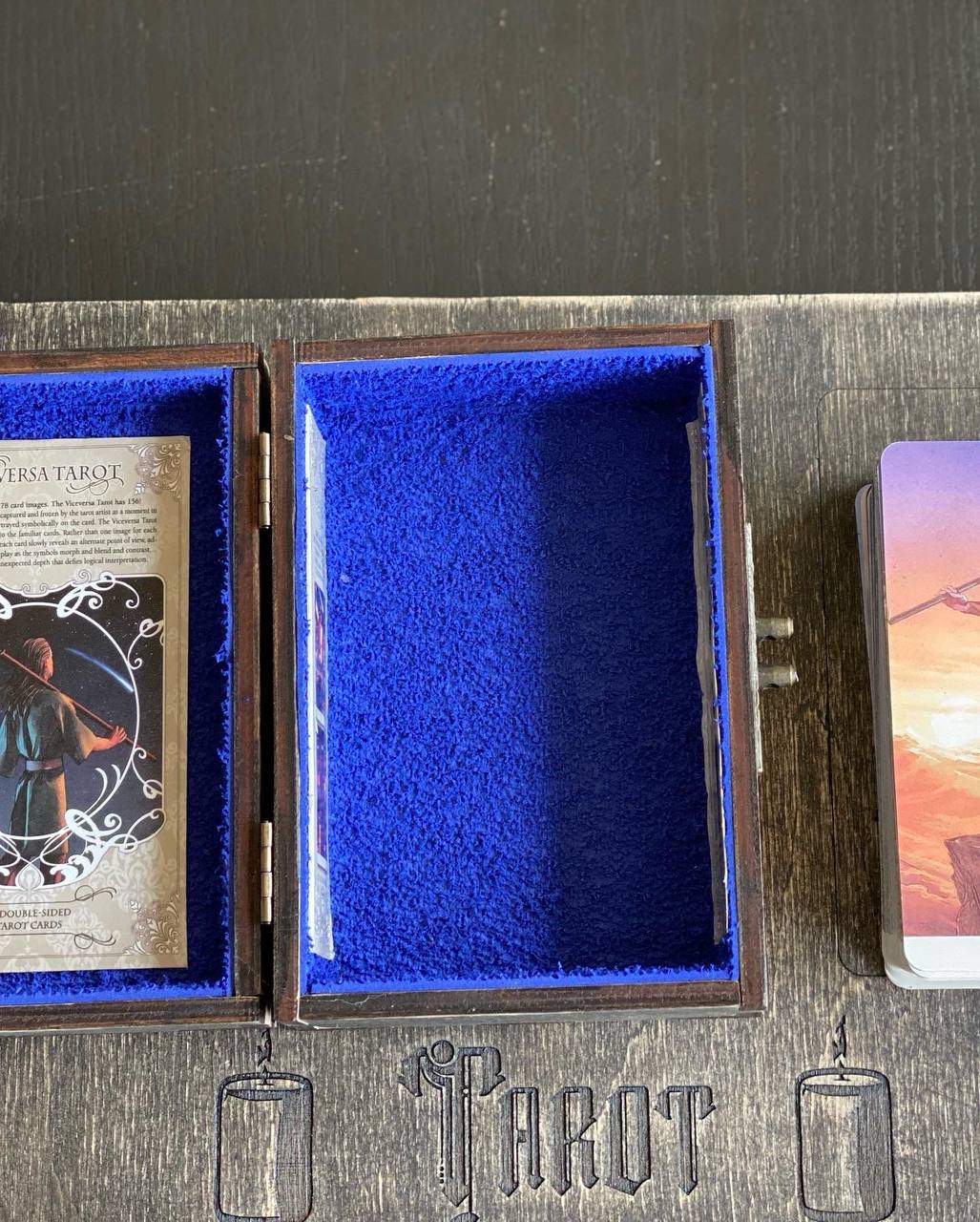 a wooden box with a blue interior, containing a tarot deck card, and a deck of playing cards.