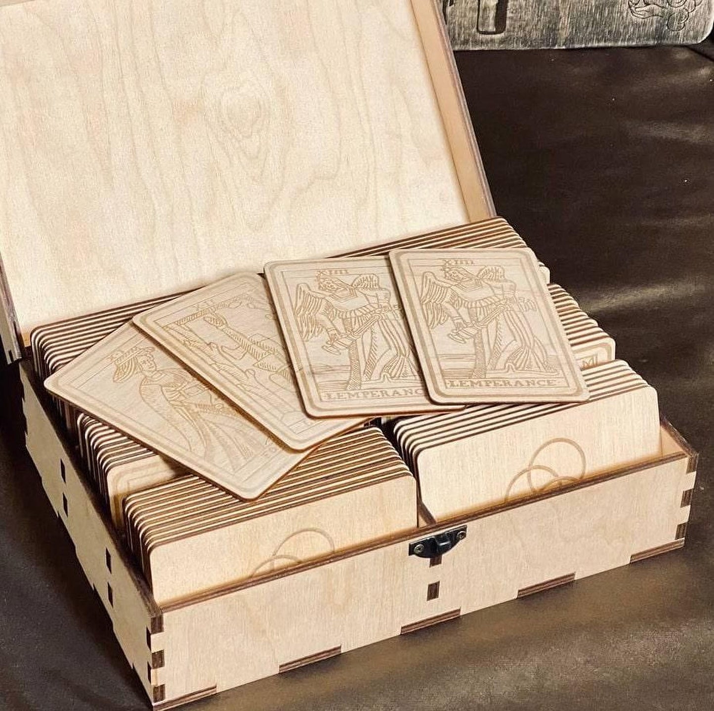 A wooden box containing several wooden tarot cards, with the cards arranged in rows inside the box.