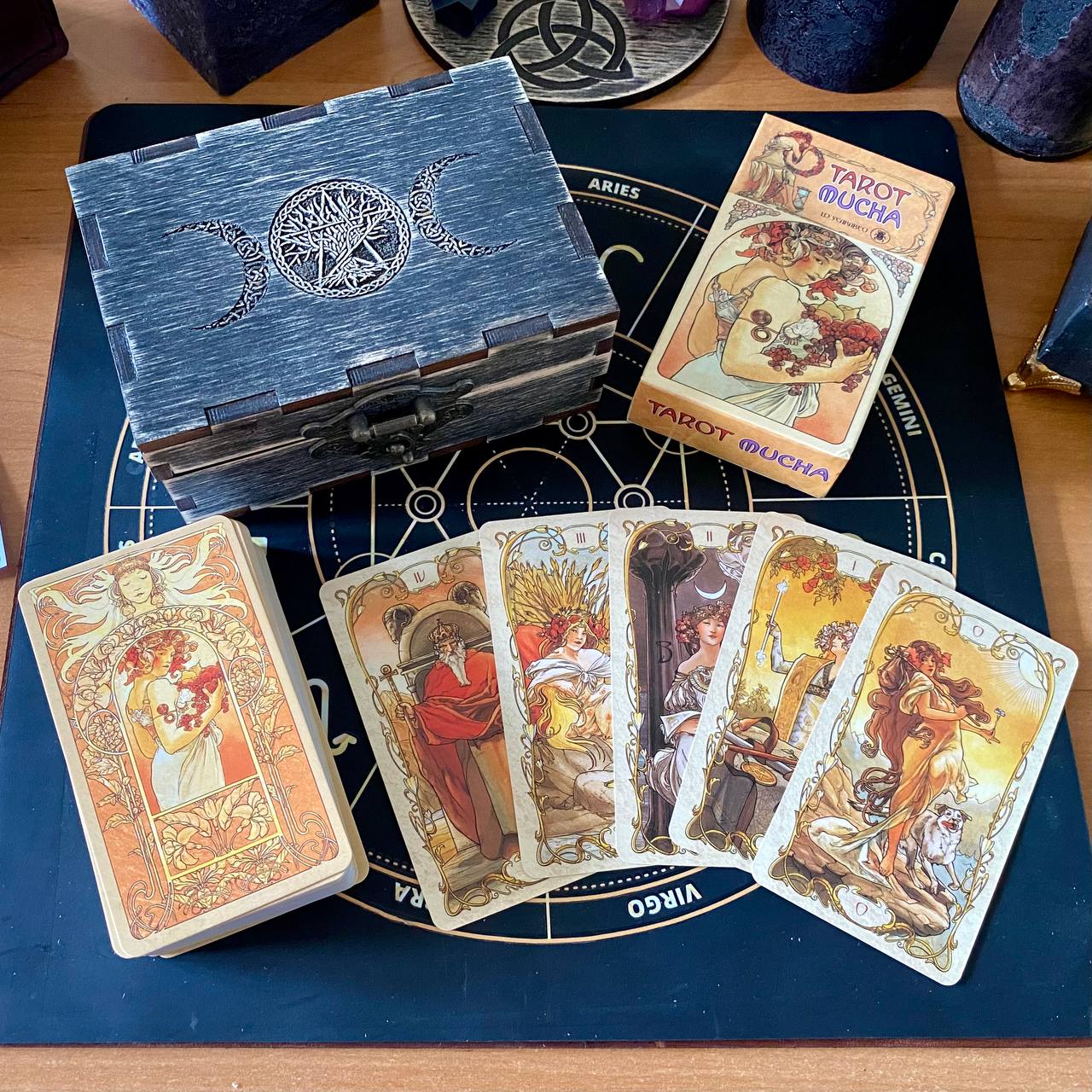 a tarot deck with a wooden box, a stack of cards, and a tarot card reader's mat.